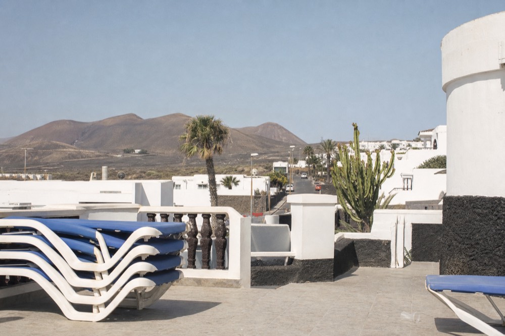 A white Lanzarote hotel terrace with volcanic hills behind it