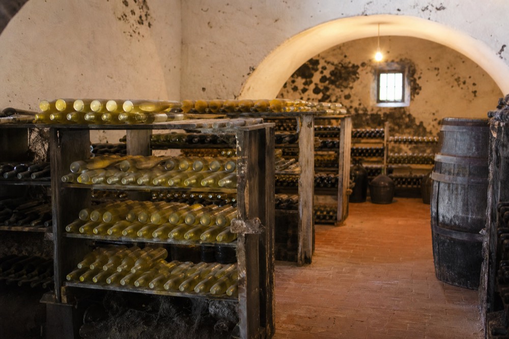Bottles of white wine stacked in a cool stone cellar of a Lanzarote winery