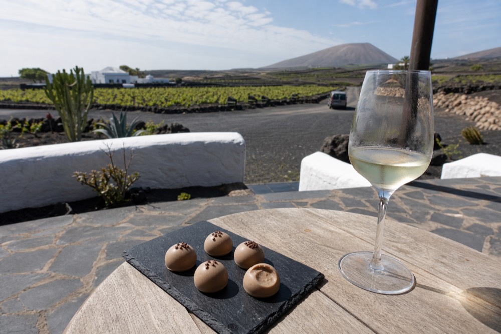 Artisan chocolate bonbons beside a glass of white wine on a stone terrace