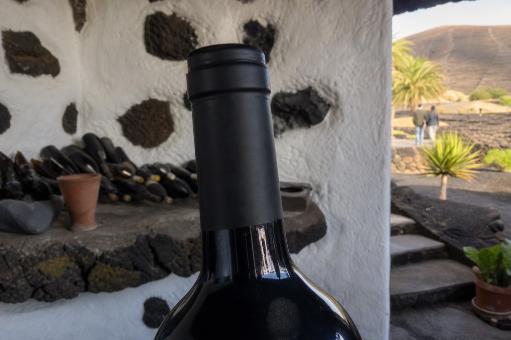 Close view of a wine bottle neck and capsule seal in a bodega