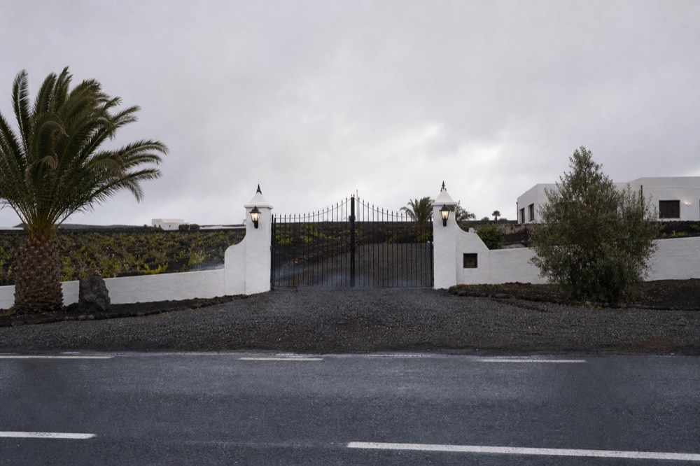 A bodega entrance gate with opening hours sign